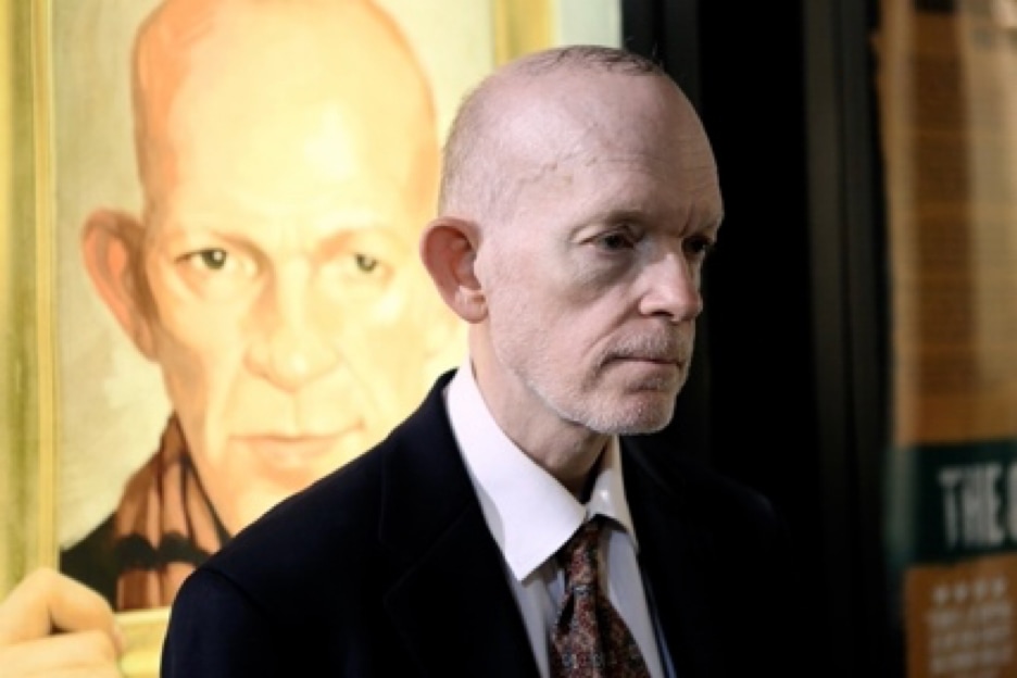 Photo of Mark Landis standing in front of a projected image of Mark
